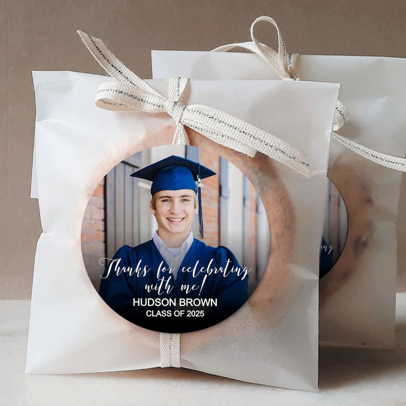Peut inclure: Des sachets cadeaux blancs avec un autocollant rond repr&eacute;sentant un dipl&ocirc;m&eacute; portant une toque et une robe bleues. L'autocollant indique "Merci d'avoir c&eacute;l&eacute;br&eacute; avec moi !"  "HUDSON BROWN"  "CLASSE DE 2025"