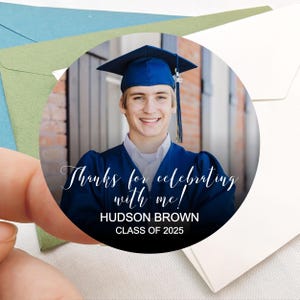 Peut inclure: Autocollant rond de remerciement pour la remise de dipl&ocirc;me avec une photo d'un dipl&ocirc;m&eacute; portant une toque et une robe bleues. Le texte indique "Merci d'avoir c&eacute;l&eacute;br&eacute; avec moi ! HUDSON BROWN CLASSE DE 2025".