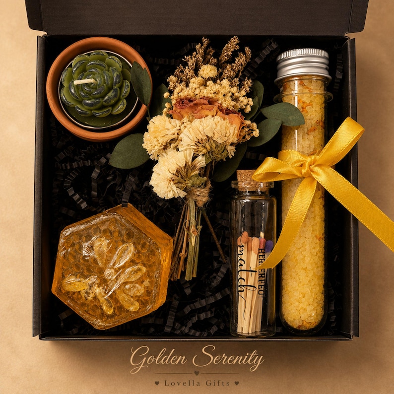 May include: A black gift box containing a green succulent candle in a terracotta pot, a dried flower bouquet, a hexagonal amber soap, a glass vial of yellow bath salts with a yellow ribbon, and a glass bottle of matches labelled with the word match.