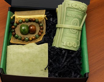 May include: A gift box with a green and black theme. Inside are a green soap bar, a beaded bracelet, a small pouch, and a stack of green money-shaped items. The box is labeled "Box 47".