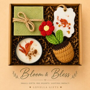 May include: A gift box containing a square green soap tied with twine, a white wax tablet with dried petals, a round candle with orange botanicals, and a crocheted flower in a brown pot. Text reads Bloom & Bless, Small Gifts. Big Hearts. Lasting Impact. Lovella Gifts.