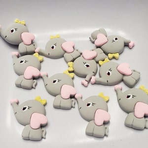 May include: A set of ten gray elephant-shaped charms with pink hearts and yellow bows. The charms are made of polymer clay and are perfect for adding a touch of whimsy to your crafts.