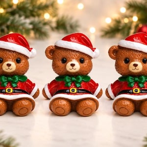 May include: Three identical brown teddy bear figurines wearing red Santa hats with white trim, red coats with white cuffs, black belts with gold buckles, and green bows around their necks. The bears have dark eyes and light brown muzzles.