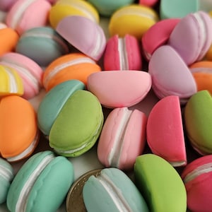 May include: A collection of colorful macarons in various pastel shades, including pink, green, blue, yellow, and purple. The macarons are arranged in a random pattern, showcasing their delicate and intricate designs.