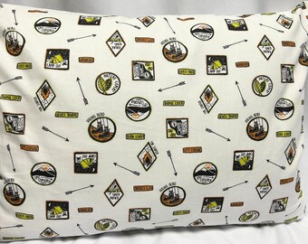 May include: White pillowcase with a repeating pattern of camping and nature-themed patches. The patches are in various shapes and colors, including green, brown, orange, and black. The patches feature text such as "Camp Out", "Hiking Hero", "Nature Expert", and "Animal Expert".