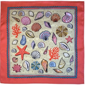 May include: Square scarf with a coral border and a light beige background. The scarf features a pattern of various seashells, starfish, and coral in shades of pink, orange, and brown. A blue border with a wave design frames the seashell pattern.