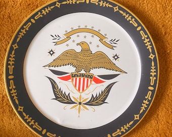 May include: A white metal serving tray with a black and gold border. The center of the tray features a gold eagle with a red, white, and blue shield, surrounded by stars and a banner.