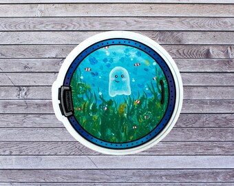 May include: A round sticker with a blue and white border. Inside the border is a blue and green underwater scene with a white ghost with a smiling face. The ghost is surrounded by seaweed and fish.