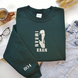 May include: A dark green sweatshirt with a white graphic of Imran Khan's face and the text "Imran Khan" printed vertically. The number "804" is printed on the left sleeve.