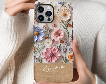 May include: A phone case with a floral design featuring pink, white, and blue flowers. The case has a burlap texture and the name "Sophia" is printed on the bottom.