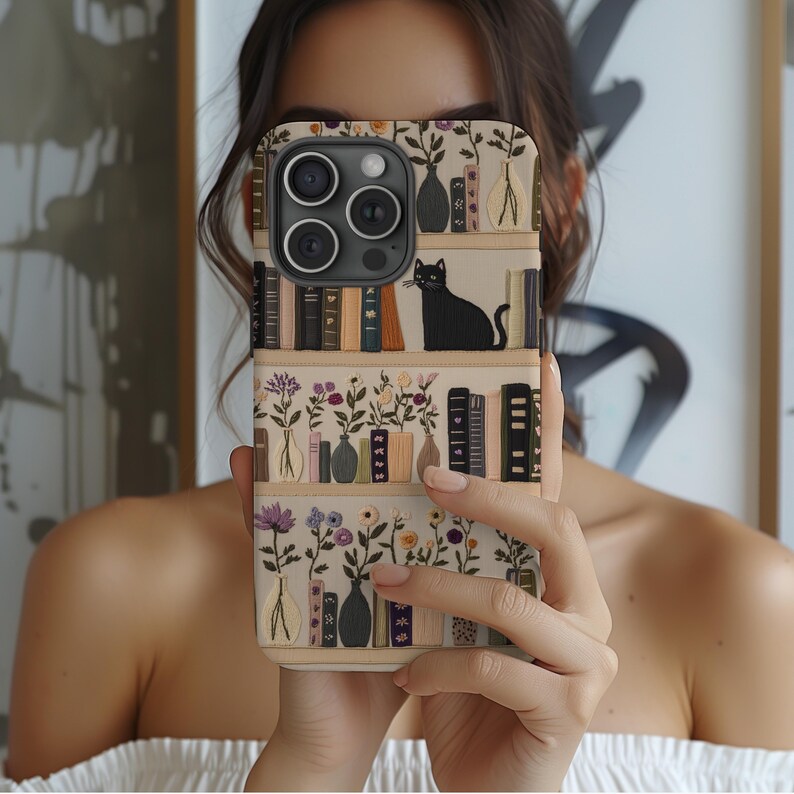 Embrace books and nature with our Bookish Boho Floral Phone Case.  Designed with book lovers in mind, this faux embroidery cat on bookshelf phone case features a flat surface print of shelved books, a cat and flowers on a vintage look background