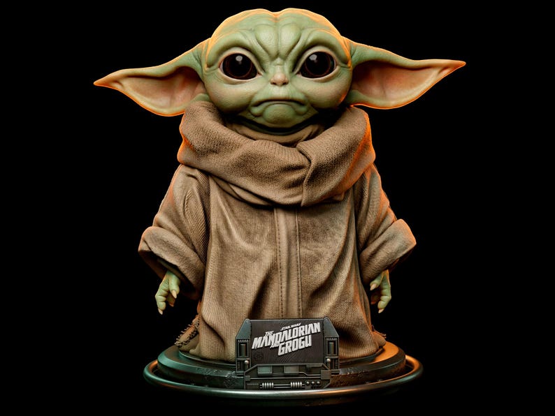 Pu&ograve; includere: Una statuetta dettagliata di Grogu, noto anche come Baby Yoda, da The Mandalorian. La figura ha grandi occhi neri, pelle verde e grandi orecchie. Grogu indossa una veste marrone e si trova su una base nera con la scritta "The Mandalorian Grogu".