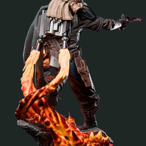 May include: A detailed figurine of a character in a dark brown and black outfit, with a jetpack and a blaster pistol. The figure is standing on a rocky base with orange and yellow flames. The character has a green head and a tan scarf.