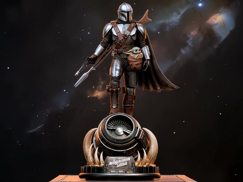 May include: A detailed statue of The Mandalorian holding a weapon, with Grogu in a pouch. The figure is clad in silver and brown armor, standing atop a detailed base. The background is a dark space scene with stars.
