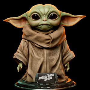 Pu&ograve; includere: Statua dettagliata di Grogu, noto anche come Baby Yoda, da The Mandalorian. La figura ha grandi occhi espressivi, orecchie a punta e indossa una veste marrone. Una piccola targa alla base recita "The Mandalorian Grogu."