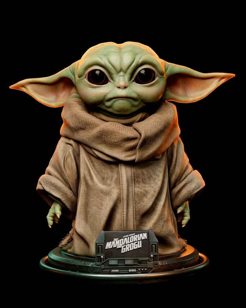 Pu&ograve; includere: Statua dettagliata di Grogu, noto anche come Baby Yoda, da The Mandalorian. La figura ha grandi occhi espressivi, orecchie a punta e indossa una veste marrone. Una piccola targa alla base recita "The Mandalorian Grogu."