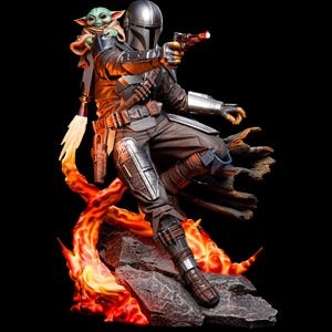 May include: A detailed figurine of The Mandalorian, in silver and brown armour, aiming a blaster with a red beam. Grogu, the Child, sits on his shoulder. The figure is posed on a rocky base with fiery orange and yellow accents, against a black background.