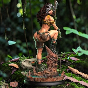 Può includere: Statuetta dettagliata di una guerriera in un ambiente giungla. La figura ha capelli castani con striature bianche, indossa un abito verde e beige. Posa con un'arma, in piedi su una base con un teschio e una fontana. Lo sfondo è una lussureggiante foresta verde.