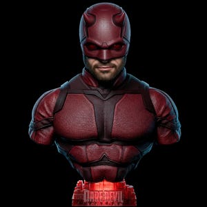 Puede incluir: Un busto del superhéroe Daredevil de Marvel Comics, con un casco rojo con cuernos y un traje rojo texturizado. El busto está sobre un fondo negro, con el nombre "DAREDEVIL" iluminado en rojo en la base.