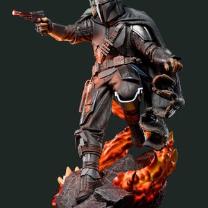 May include: A detailed figurine of a character in dark armour, holding a blaster pistol with a red light. The figure is posed on a rocky base with fiery orange and yellow accents. A cape and helmet complete the look.
