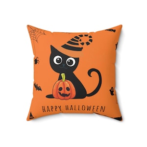 May include: Orange cushion with a black cat wearing a witch's hat and holding a jack-o'-lantern. The cushion has the text "Happy Halloween" on it.