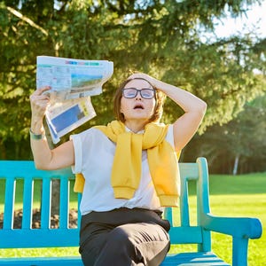Może przedstawiać: Osoba siedząca na niebieskiej ławce w parku, trzymająca gazetę przed twarzą. Ma na sobie okulary, białą koszulę, ż&oacute;łty sweter i czarne spodnie. Tło obejmuje zielone drzewa i trawę.