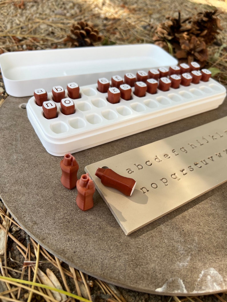 Alphabet letter stamps for impressions in clay or soap making.  Holder box with lid.