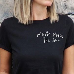 May include: Black t-shirt with white text that reads "music heals the soul" in a handwritten style.