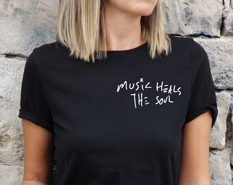 May include: Black t-shirt with white text that reads "music heals the soul" in a handwritten style.