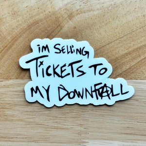 May include: White sticker with black handwritten text that reads "I'm selling tickets to my downfall."