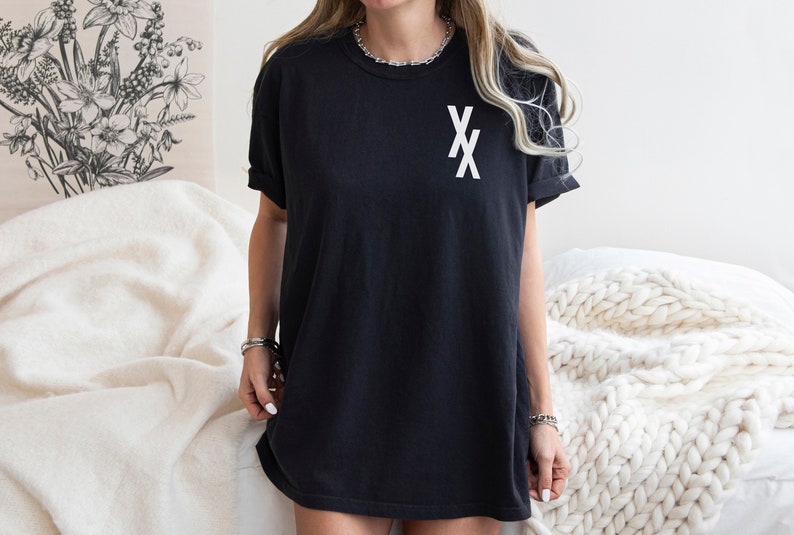 May include: A black oversized t-shirt with a white graphic of two overlapping 'X's on the front.