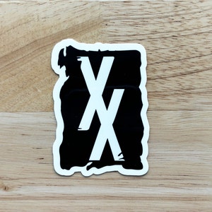 Könnte beinhalten: Schwarz-weißer Aufkleber mit einem stilisierten "XX"-Design. Der Aufkleber hat einen abgenutzten, handgemalten Look.