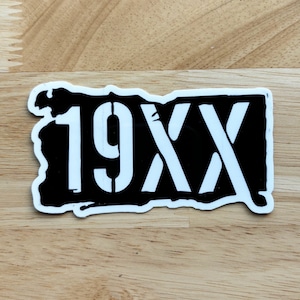 May include: Black and white sticker with the text "19XX" in a distressed font.
