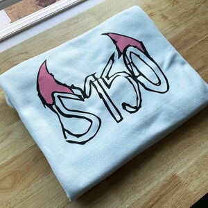 May include: A light blue t-shirt with a black and pink graphic design that says "5150".