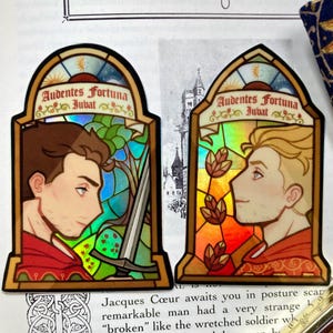 May include: Two stickers with stained glass designs. Each features a profile of a person with the text "Audentes Fortuna Jubat". One has a sword and green and blue hues, the other has autumn leaves and orange hues.