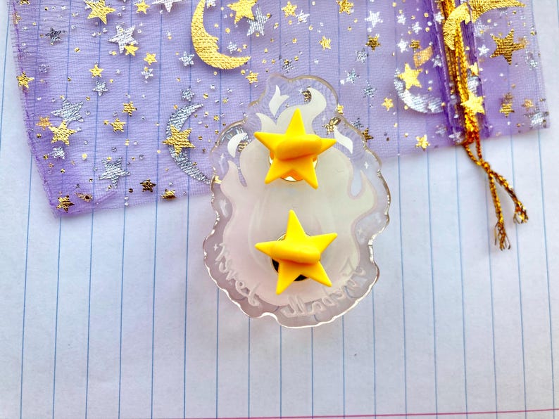 May include: A pair of yellow star-shaped earrings on a clear plastic display card with the word "Sweet" written on it.