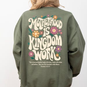 May include: Green sweatshirt with a retro-style graphic that says "Motherhood is Kingdom Work" with flowers and a quote from Proverbs 31:25-27.