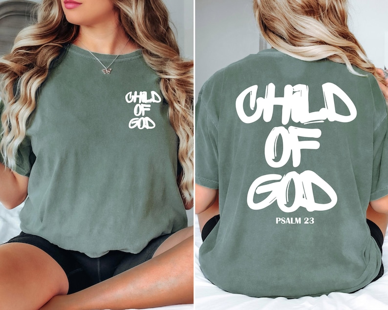 May include: Sage green t-shirt with the text "CHILD OF GOD" in white on the front and back. The back of the shirt also includes "PSALM 23" in white. The shirt is a short-sleeved, crew neck style.