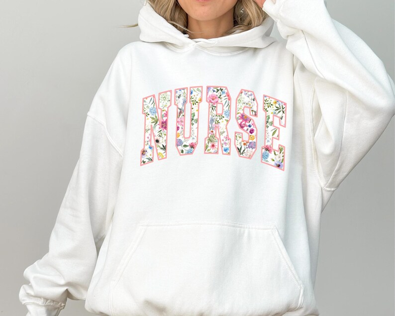 May include: White hoodie with a floral print of the word "NURSE" on the front.