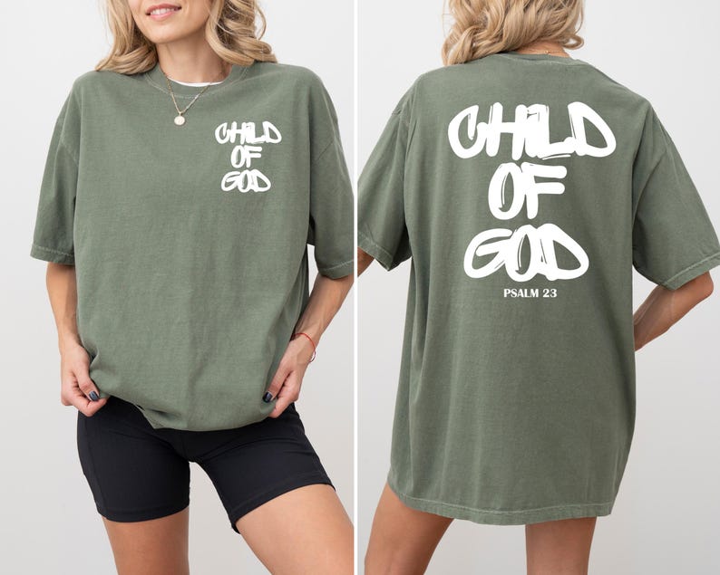 May include: Olive green t-shirt with the text "CHILD OF GOD" in white on the front and back. The back of the shirt also includes "PSALM 23". The shirt is a relaxed fit.