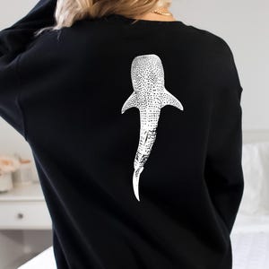 May include: Black sweatshirt with a white whale shark graphic on the back.