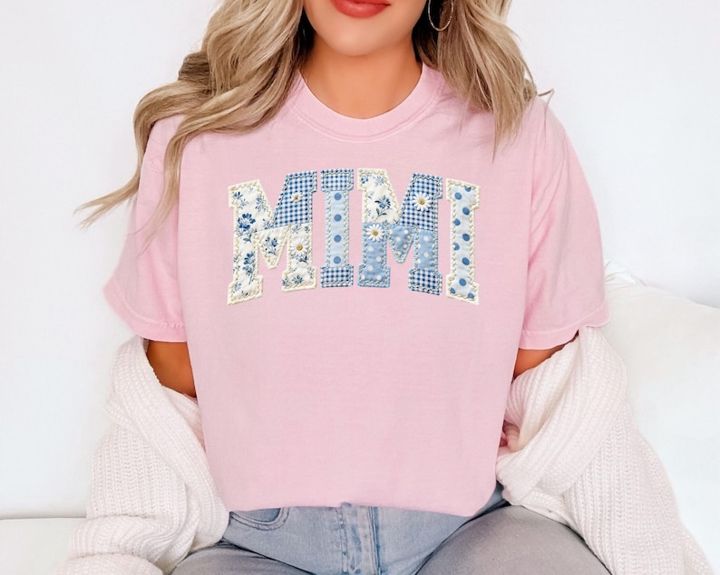 K&ouml;nnte beinhalten: Ein hellrosa T-Shirt mit dem Wort "MIMI" in einem Patchwork-Design. Die Buchstaben bestehen aus blau-wei&szlig;en Blumen- und Tupfenmustern. Das Shirt ist ein l&auml;ssiger Stil.