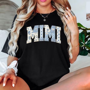K&ouml;nnte beinhalten: Schwarzes T-Shirt mit dem Wort "MIMI" in einem Patchwork-Design. Die Buchstaben sind eine Mischung aus blauem Vichy, floralen und einfarbigen Mustern. Das Shirt ist ein l&auml;ssiger Stil.