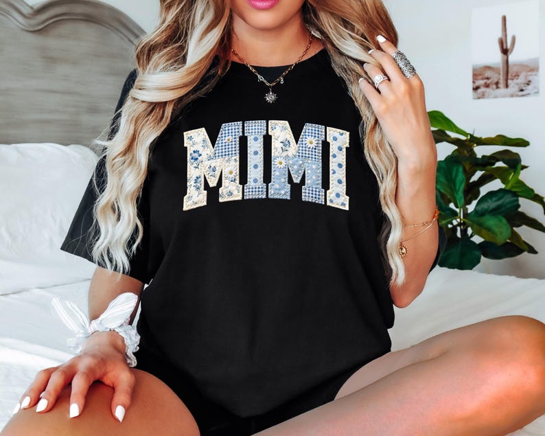 K&ouml;nnte beinhalten: Schwarzes T-Shirt mit dem Wort "MIMI" in einem Patchwork-Design. Die Buchstaben sind eine Mischung aus blauem Vichy, floralen und einfarbigen Mustern. Das Shirt ist ein l&auml;ssiger Stil.