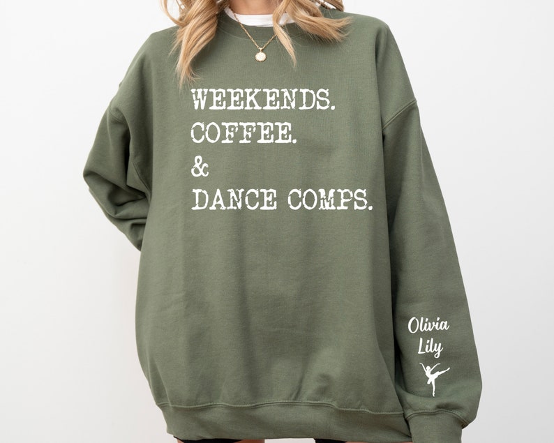 Op de afbeelding: Groen sweatshirt met de tekst "Weekends. Coffee. & Dance Comps." in wit. De rechtermouw heeft de tekst "Olivia Lily" en een wit silhouet van een danseres.