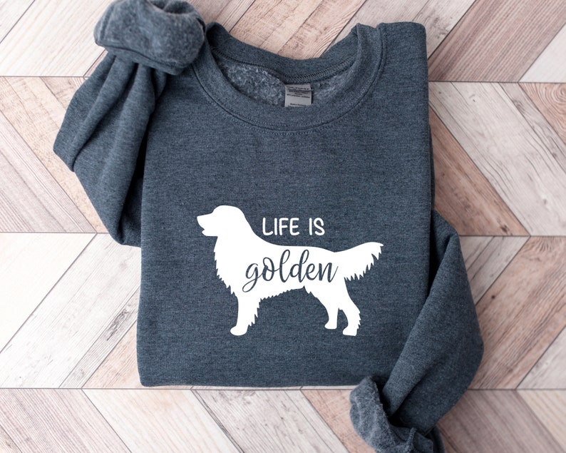 Pu&ograve; includere: Una felpa grigia scura con una silhouette bianca di un golden retriever e il testo "Life is golden".