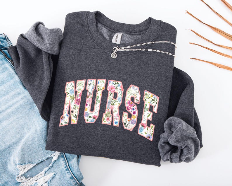 May include: A dark gray sweatshirt with a floral print of the word "NURSE" in pink.
