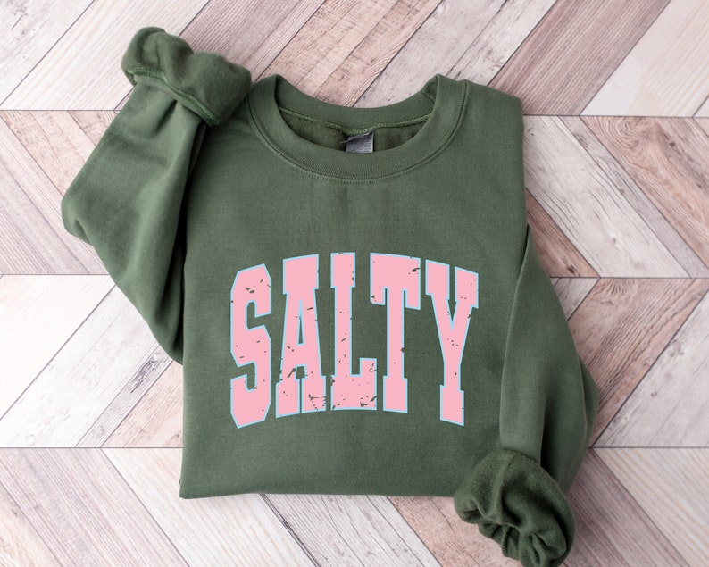 May include: A green sweatshirt with the word "SALTY" printed in pink letters with a distressed look.