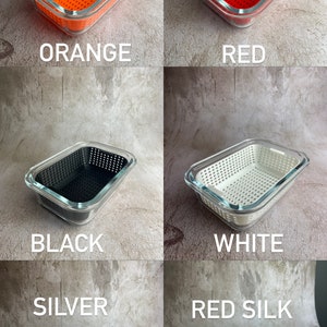 May include: A selection of rectangular food storage containers in colours including orange, red, black, white, and silver. Each container has a clear glass exterior and a perforated interior. A red brick-shaped object is also shown.