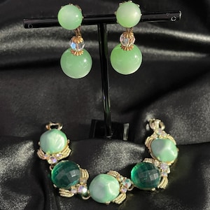 May include: A set of green and clear glass earrings and a bracelet with green and clear glass stones. The earrings are dangle style and the bracelet is a link style.